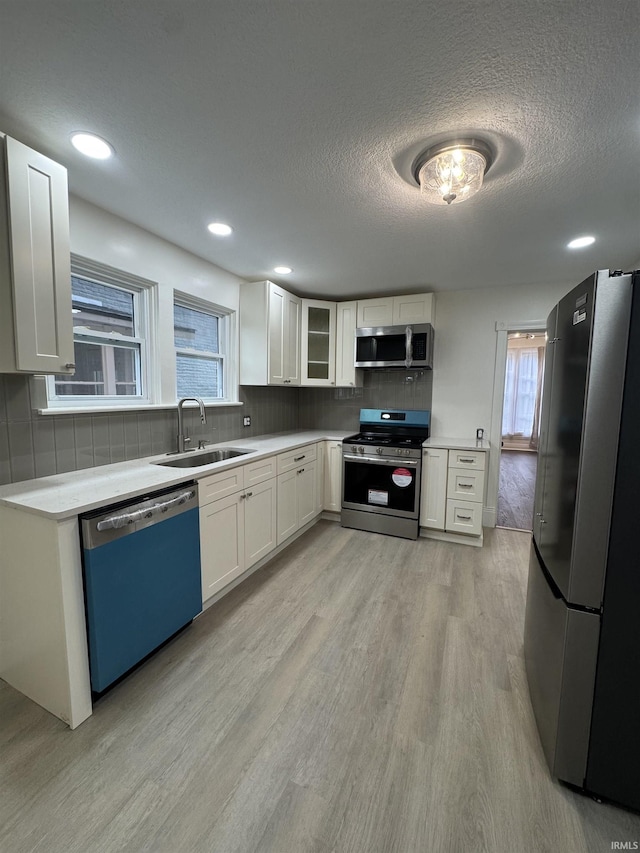 241 W Tipton St, Huntington, IN 46750 - kitchen with stainless steel appliances, light wood-style flooring, white cabinetry, tasteful backsplash, and light countertops