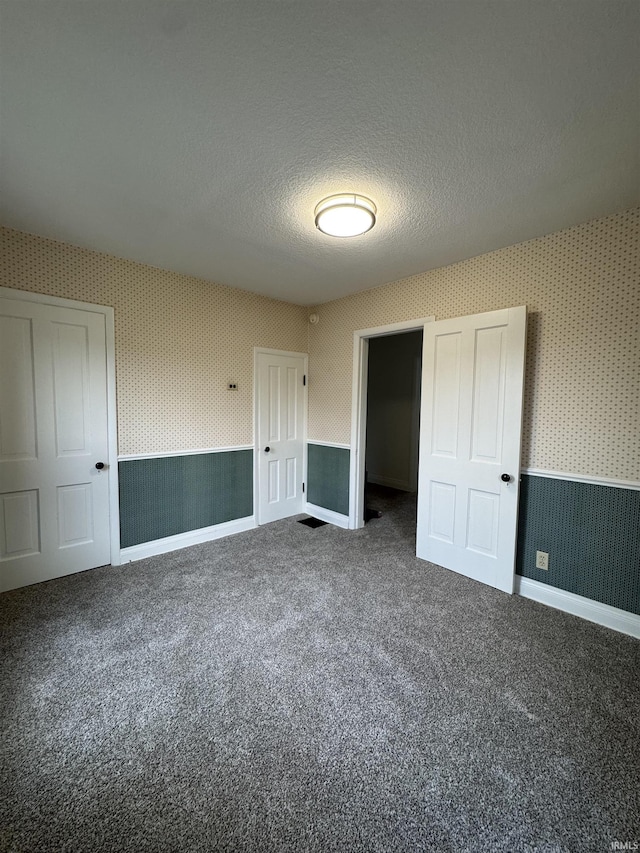 241 W Tipton St, Huntington, IN 46750 - unfurnished bedroom with wallpapered walls, carpet, a textured ceiling, and a closet