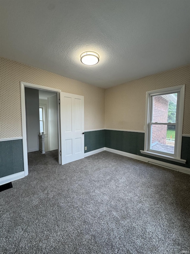 241 W Tipton St, Huntington, IN 46750 - spare room with wallpapered walls, dark carpet, and a textured ceiling