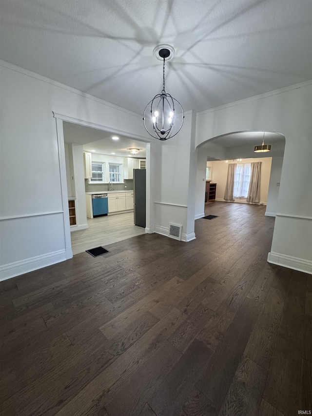 241 W Tipton St, Huntington, IN 46750 - unfurnished living room featuring arched walkways, ornamental molding, wood finished floors, and a chandelier