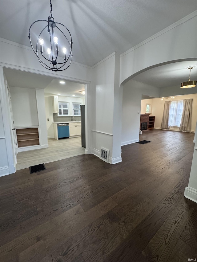 241 W Tipton St, Huntington, IN 46750 - unfurnished living room featuring arched walkways, a chandelier, crown molding, and wood finished floors