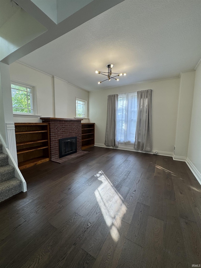 241 W Tipton St, Huntington, IN 46750 - unfurnished living room featuring dark wood-type flooring, a brick fireplace, stairway, a chandelier, and a textured ceiling