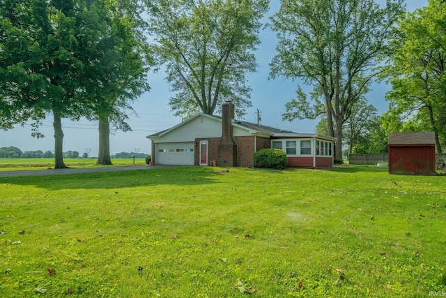 602 S Maple St, Galveston, IN 46932 - view of grassy yard with an attached garage, a storage shed, a sunroom, and driveway