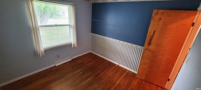 113 N Beechwood St, Warsaw, IN 46582 - spare room with wood finished floors, baseboard heating, wallpapered walls, and wainscoting