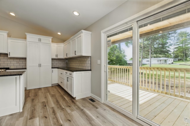 1724 28th St, Bedford, IN 47421 - kitchen with dark countertops, tasteful backsplash, lofted ceiling, white cabinets, and light wood-type flooring
