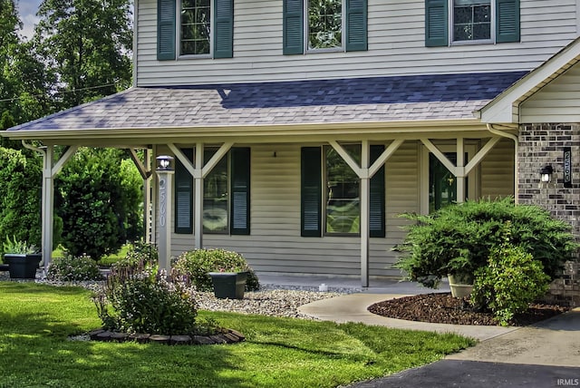 2560 E Maple Dr, Bluffton, IN 46714 - view of exterior entry featuring covered porch, a lawn, and roof with shingles