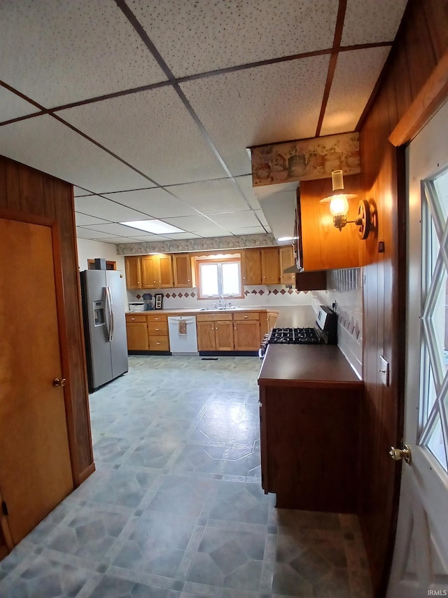 7086 S 200 E, Macy, IN 46951 - kitchen featuring appliances with stainless steel finishes, brown cabinetry, a paneled ceiling, wooden walls, and decorative backsplash