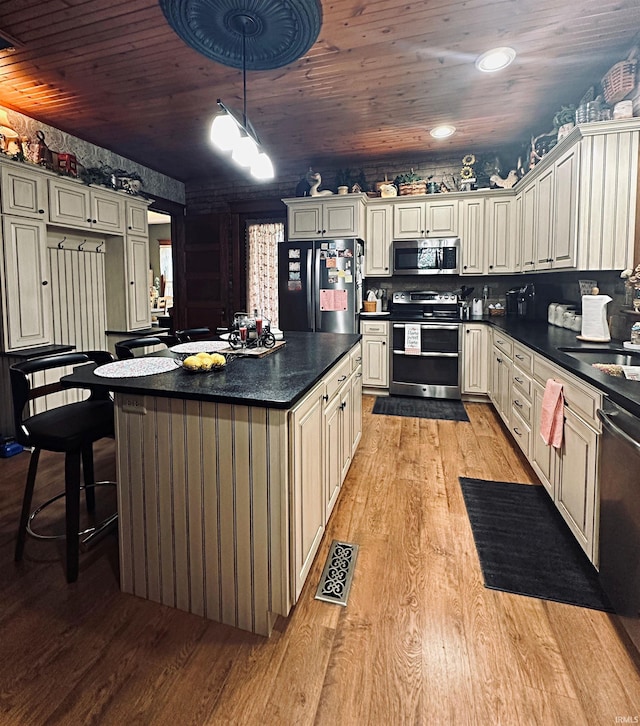 715 SE 2nd St, Washington, IN 47501 - kitchen with stainless steel appliances, light wood-style flooring, dark countertops, wooden ceiling, and a kitchen island