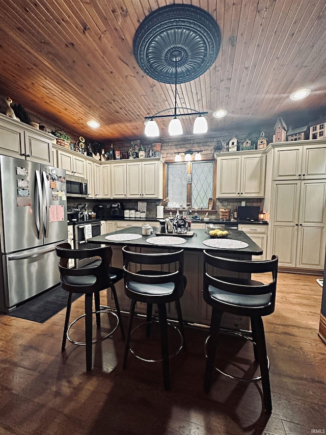 715 SE 2nd St, Washington, IN 47501 - kitchen featuring stainless steel appliances, cream cabinetry, a center island, wooden ceiling, and a kitchen bar