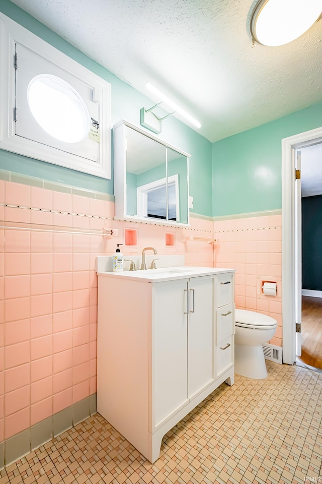 2801 W University Ave, Muncie, IN 47304 - bathroom featuring tile walls, vanity, a wainscoted wall, tile patterned floors, and a textured ceiling