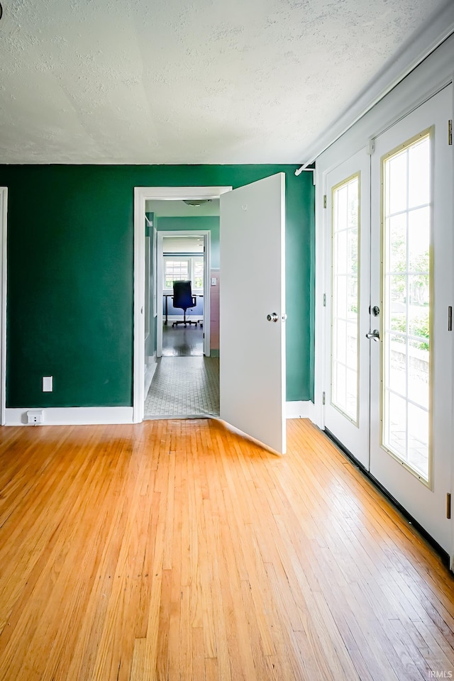 2801 W University Ave, Muncie, IN 47304 - empty room featuring light wood finished floors, a textured ceiling, and french doors