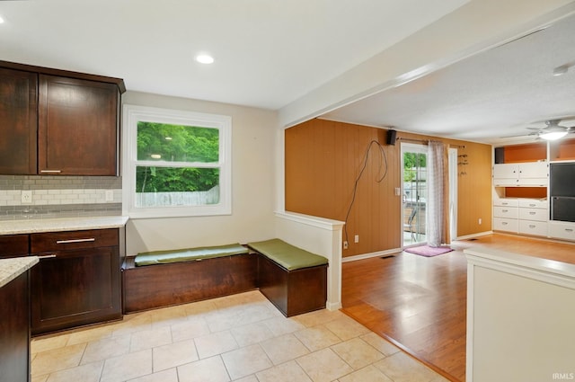 5820 Rosedale Dr, Fort Wayne, IN 46804 - kitchen featuring dark brown cabinetry, backsplash, open floor plan, a ceiling fan, and light stone counters