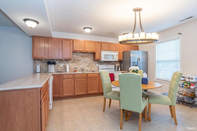 1250 W Adams Hill Cir Unit 104, Bloomington, IN 47403 - kitchen with white appliances, tasteful backsplash, light countertops, a chandelier, and decorative light fixtures