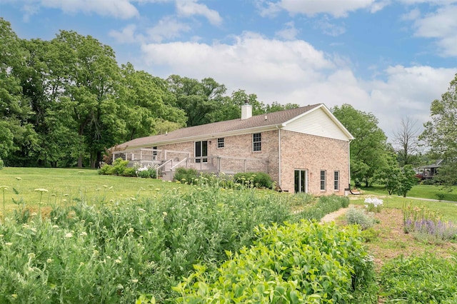 7486 S Ketcham Rd, Bloomington, IN 47403 - back of property with a chimney, a deck, brick siding, and a yard