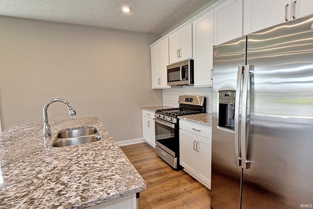 4764 Chelmsford Dr, Newburgh, IN 47630 - kitchen featuring stainless steel appliances, light wood-style floors, decorative backsplash, white cabinetry, and light stone countertops