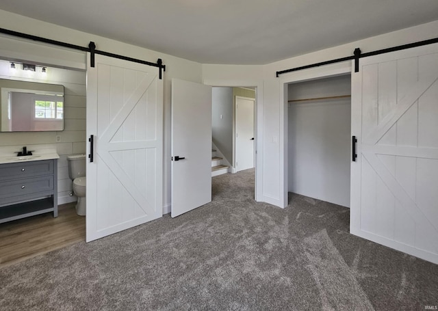 6711 Trier Rd, Fort Wayne, IN 46815 - unfurnished bedroom with a barn door, dark carpet, connected bathroom, and a closet