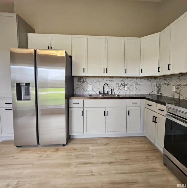 6711 Trier Rd, Fort Wayne, IN 46815 - kitchen featuring appliances with stainless steel finishes, dark countertops, white cabinetry, decorative backsplash, and light wood finished floors