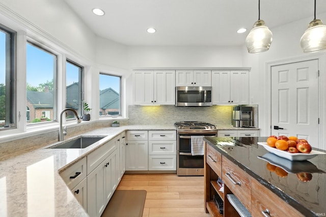12733 Covington Manor Farms Rd, Fort Wayne, IN 46814 - kitchen with stainless steel appliances, light wood-style floors, white cabinets, tasteful backsplash, and decorative light fixtures