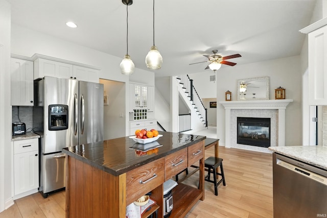 12733 Covington Manor Farms Rd, Fort Wayne, IN 46814 - kitchen featuring stainless steel appliances, a ceiling fan, light wood-style floors, white cabinetry, and a glass covered fireplace