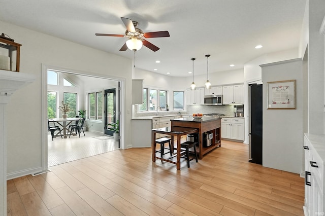 12733 Covington Manor Farms Rd, Fort Wayne, IN 46814 - kitchen featuring appliances with stainless steel finishes, a center island, ceiling fan, white cabinetry, and backsplash