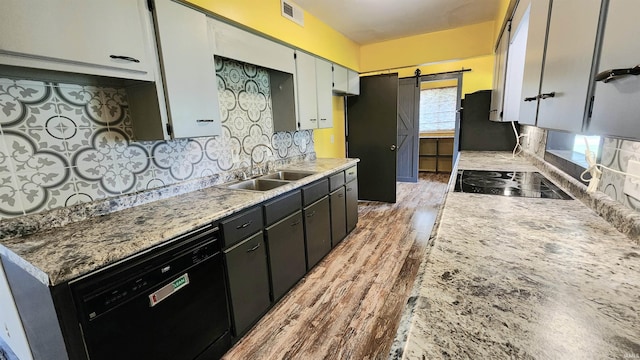 406 James St, Butler, IN 46721 - kitchen with black appliances, a barn door, tasteful backsplash, light wood finished floors, and light countertops