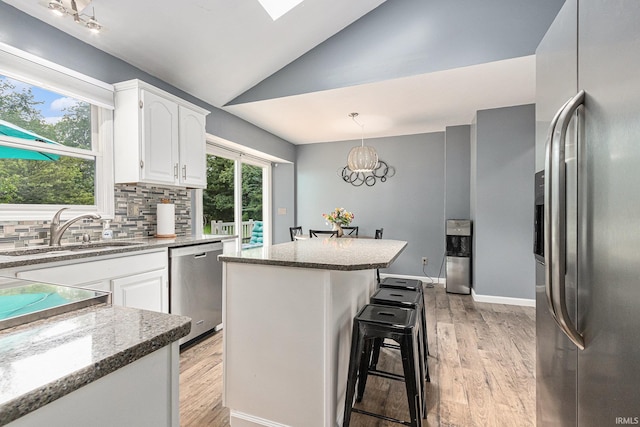 51790 Sulkey Ct, Granger, IN 46530 - kitchen featuring appliances with stainless steel finishes, lofted ceiling, tasteful backsplash, white cabinets, and light wood finished floors