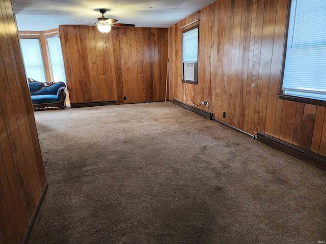 317 E Main St, Berne, IN 46711 - carpeted empty room featuring a baseboard heating unit, wood walls, and ceiling fan