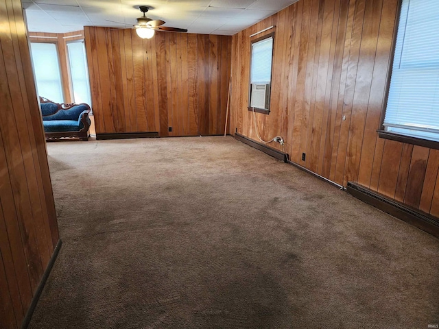 317 E Main St, Berne, IN 46711 - spare room featuring baseboard heating, carpet flooring, wood walls, a ceiling fan, and plenty of natural light