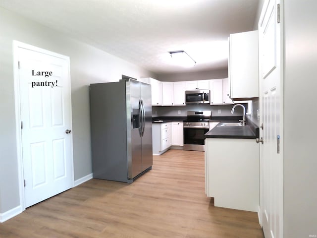 10239 State Road 26 E, Lafayette, IN 47905 - kitchen with stainless steel appliances, dark countertops, light wood-type flooring, and white cabinets