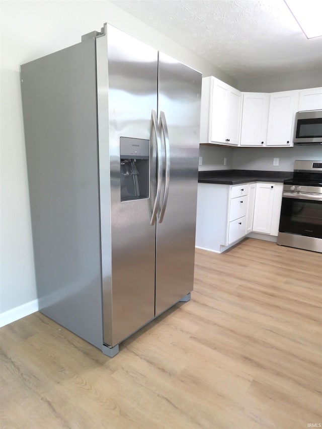 10239 State Road 26 E, Lafayette, IN 47905 - kitchen featuring appliances with stainless steel finishes, light wood-style floors, white cabinetry, and dark countertops