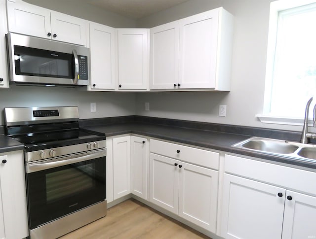 10239 State Road 26 E, Lafayette, IN 47905 - kitchen with appliances with stainless steel finishes, white cabinets, dark countertops, and light wood-style floors