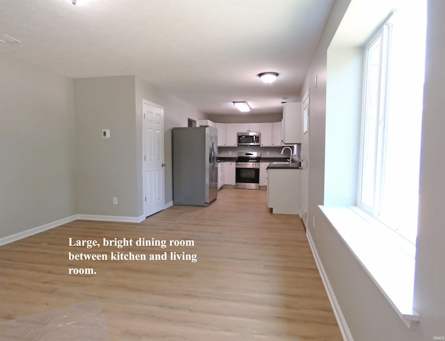 10239 State Road 26 E, Lafayette, IN 47905 - kitchen with appliances with stainless steel finishes, dark countertops, light wood-type flooring, and white cabinets