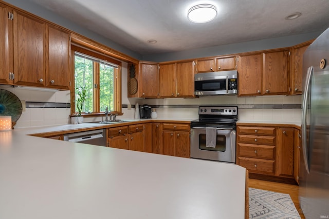 5549 S Tammany Ct, Bloomington, IN 47401 - kitchen with stainless steel appliances, brown cabinetry, backsplash, light countertops, and recessed lighting