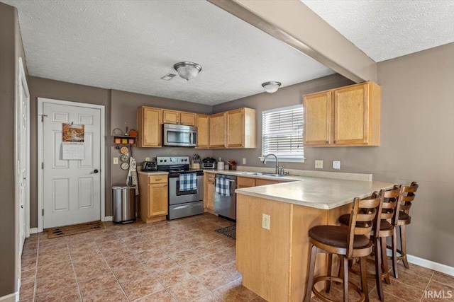 4103 Stergen Dr, Lafayette, IN 47909 - kitchen with appliances with stainless steel finishes, a peninsula, a textured ceiling, light countertops, and a breakfast bar area