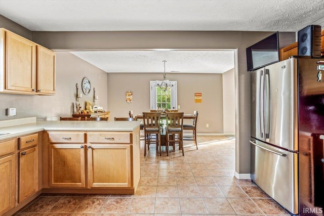 4103 Stergen Dr, Lafayette, IN 47909 - kitchen with freestanding refrigerator, a peninsula, light countertops, light tile patterned floors, and a textured ceiling