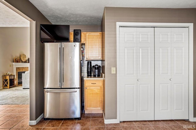 4103 Stergen Dr, Lafayette, IN 47909 - kitchen with freestanding refrigerator, a textured ceiling, dark tile patterned flooring, a glass covered fireplace, and light countertops