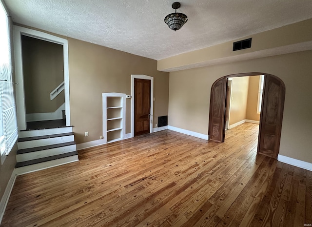 709 W Main St, Ellettsville, IN 47429 - spare room with wood-type flooring, arched walkways, a textured ceiling, and stairway