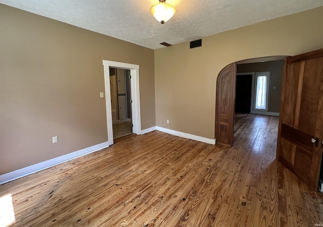 709 W Main St, Ellettsville, IN 47429 - unfurnished room featuring arched walkways, hardwood / wood-style flooring, and a textured ceiling