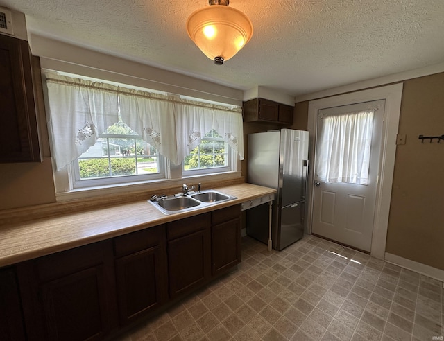 709 W Main St, Ellettsville, IN 47429 - kitchen featuring freestanding refrigerator, light countertops, a textured ceiling, dark brown cabinetry, and light flooring