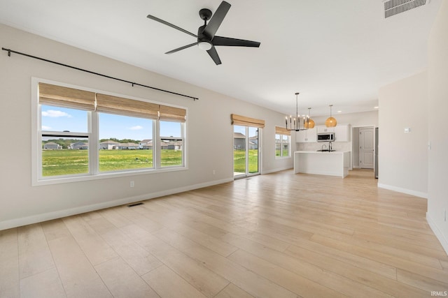 17464 Sonic Ct, Huntertown, IN 46748 - unfurnished living room featuring a chandelier, ceiling fan, and light wood-style floors