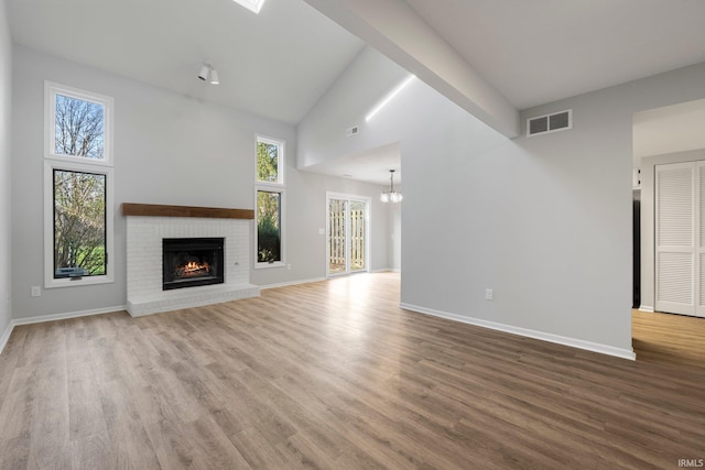 7104 Thamesford Dr Unit 83, Fort Wayne, IN 46835 - unfurnished living room featuring wood finished floors, a brick fireplace, a chandelier, and a high ceiling
