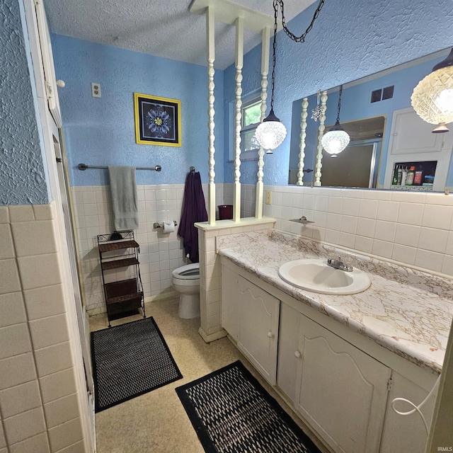 989 S Cataract Rd, Spencer, IN 47460 - full bath featuring tile walls, vanity, a textured wall, a textured ceiling, and wainscoting