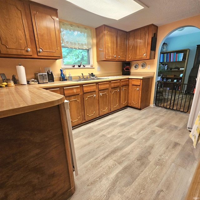 989 S Cataract Rd, Spencer, IN 47460 - kitchen featuring brown cabinetry, light wood-style flooring, arched walkways, and butcher block countertops