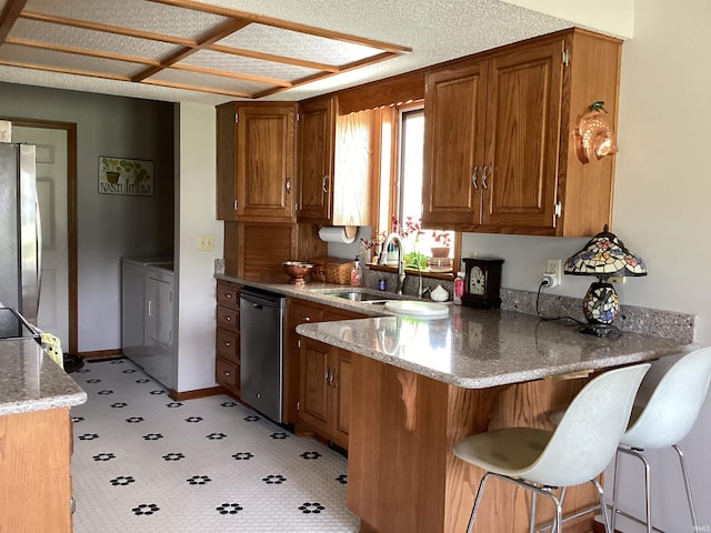 1016 E Monroe St, Decatur, IN 46733 - kitchen featuring appliances with stainless steel finishes, washing machine and clothes dryer, a peninsula, brown cabinetry, and light stone countertops