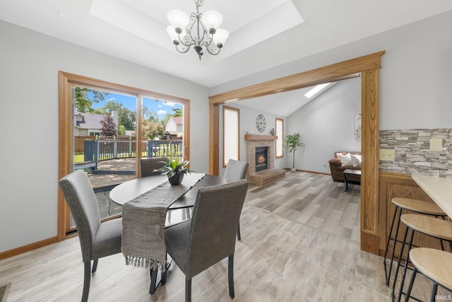 2319 Autumn Lake Pl, Fort Wayne, IN 46818 - dining space with a chandelier, light wood-style flooring, a lit fireplace, a tray ceiling, and lofted ceiling