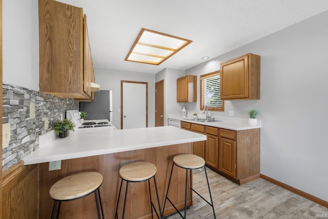 2319 Autumn Lake Pl, Fort Wayne, IN 46818 - kitchen featuring a breakfast bar area, a peninsula, light countertops, light wood finished floors, and stove