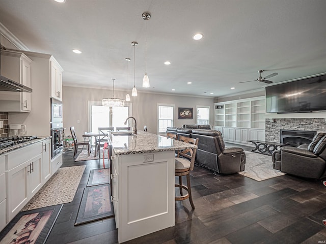 4261 Martha Ct, Newburgh, IN 47630 - kitchen featuring stainless steel appliances, ceiling fan, open floor plan, a stone fireplace, and a center island with sink