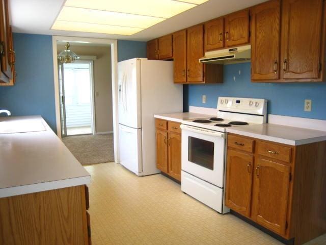 52289 Wembley Dr, South Bend, IN 46637 - kitchen featuring under cabinet range hood, white appliances, brown cabinets, and light countertops