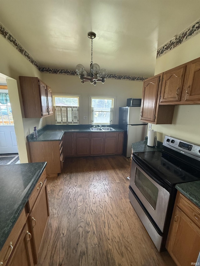 923 W Jackson St, Kokomo, IN 46901 - kitchen featuring appliances with stainless steel finishes, a chandelier, dark wood-style floors, dark countertops, and brown cabinetry