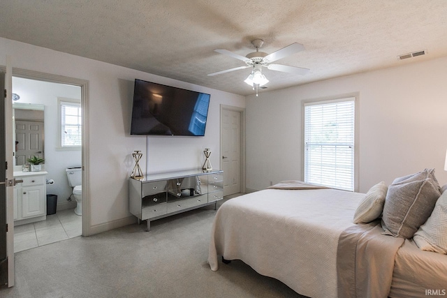 2123 Bunker Ln, Evansville, IN 47725 - bedroom with multiple windows, connected bathroom, a textured ceiling, light colored carpet, and a ceiling fan